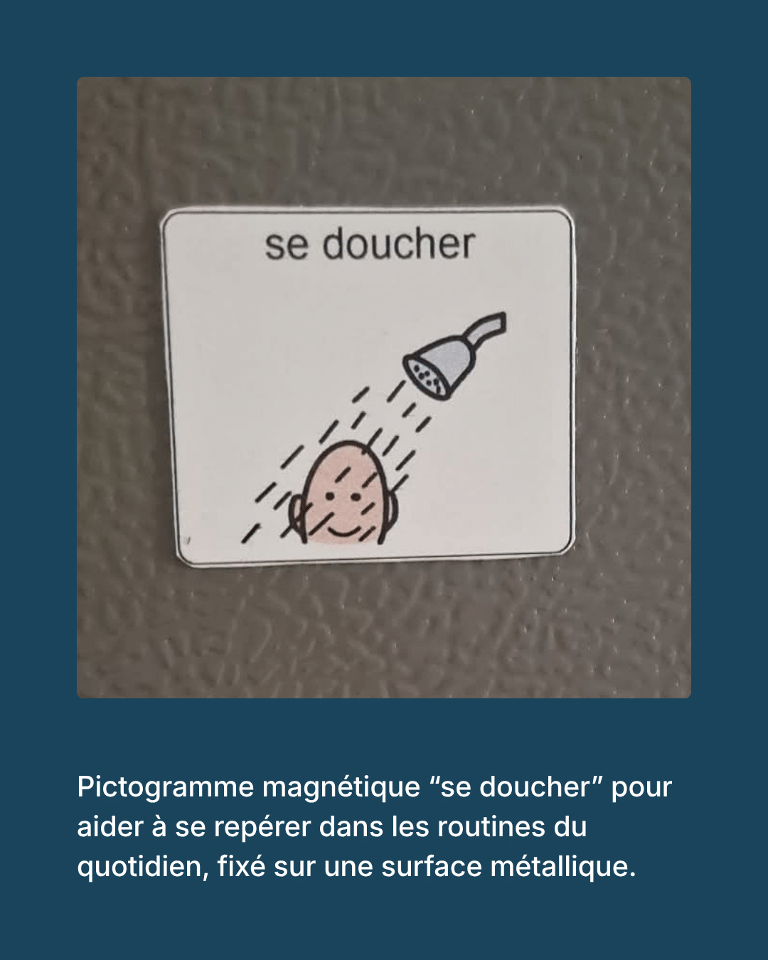 Pictogramme magnétique « se doucher » montrant un visage souriant sous une pomme de douche, fixé sur une surface métallique grise.