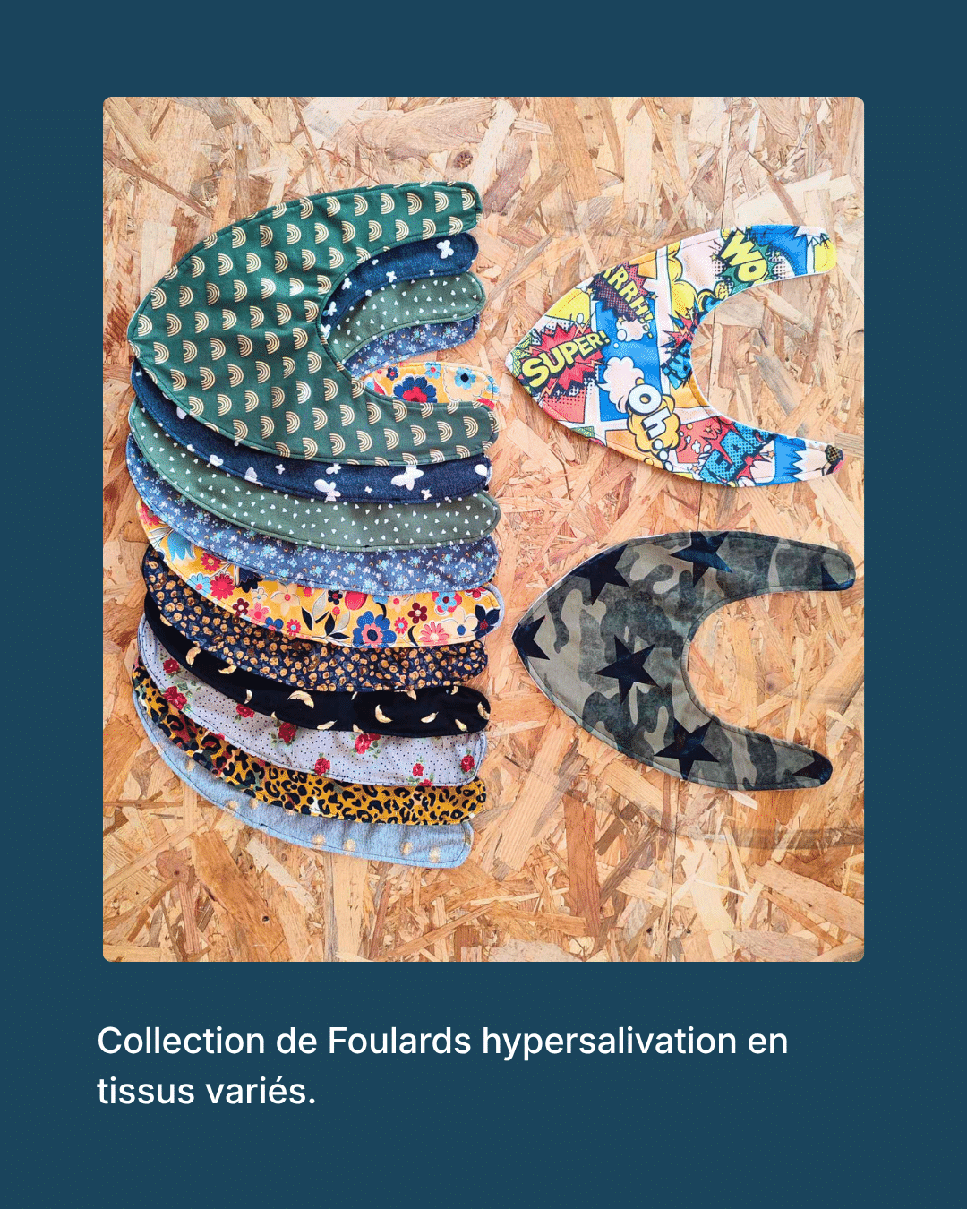 Collection de foulards pour hypersalivation en tissus variés (motifs arcs-en-ciel, fleurs, léopard, camouflage à étoiles, style bande dessinée), disposés à plat sur un panneau de bois.