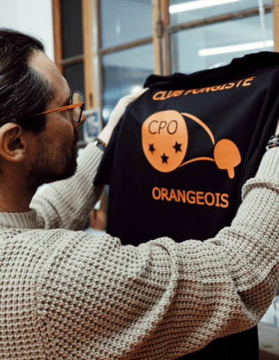 Arnaud examine un vêtement noir imprimé pour vérifier la qualité de la pose.